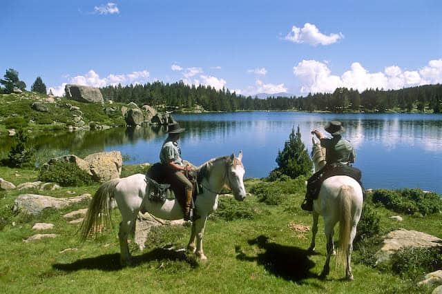 Plein air au bord du lac avec deux cavaliers et chevaux.